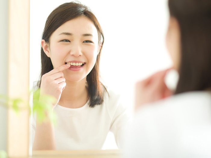 鏡で自分の歯を見る女性